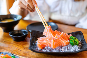 Young asian woman eating sashimi set in japanese restaurant