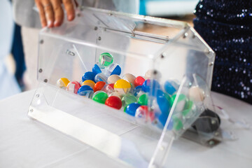 Process of prize drawings, extracting a winning numbers of lottery machine, raffle drum with bingo balls and winning tickets on event with a host and hands on lottery machine