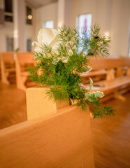 Weiße Rose in der Kirche an der Kirchenbank als Blumengesteck