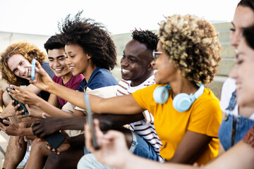 Young group of multiracial people using smartphone outdoors - Addicted milllennial friends sharing...