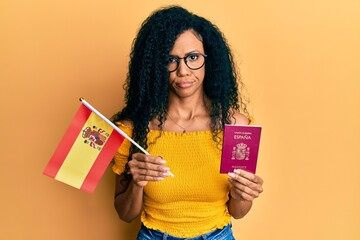 Middle age african american woman holding spain flag and passport skeptic and nervous, frowning...