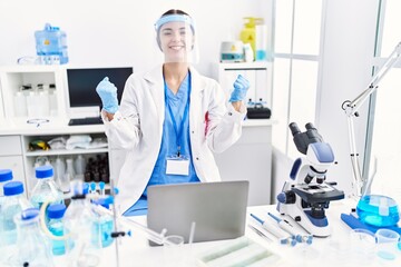 Young hispanic woman wearing scientist uniform screaming proud, celebrating victory and success...