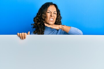 Middle age hispanic woman holding blank empty banner cutting throat with hand as knife, threaten aggression with furious violence