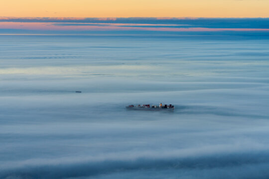 Aerial view of a cargo ship sailing goff Cape Town coastline during a foggy day, Cape Town, South Africa.