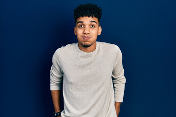 Young african american man wearing casual clothes puffing cheeks with funny face. mouth inflated with air, crazy expression.