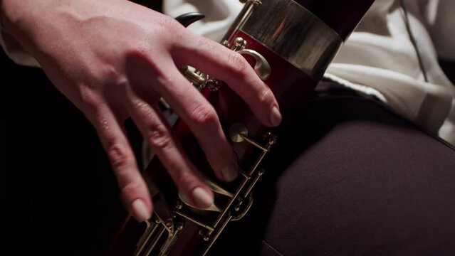 Closeup of fingers female musician playing jazz on bassoon at studio. Female musician plays at bassoon with fingers on keys