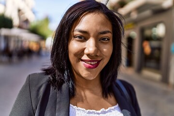 Beautiful hispanic woman smiling at the camera, walking outdoors on a sunny day. Young latina girl...