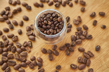 Coffee beans in a transparent bowl over a wood tablet with copy space.