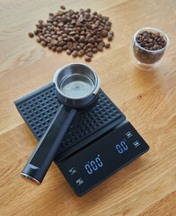 Coffee maker horn lies on coffee scales, on the background of wooden countertops, coffee beans