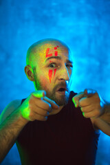 Stylish bald man points fingers at camera. Fluorescent paint in neon light. Way to meet in nightclub.