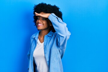 Young african american woman wearing casual clothes very happy and smiling looking far away with hand over head. searching concept.