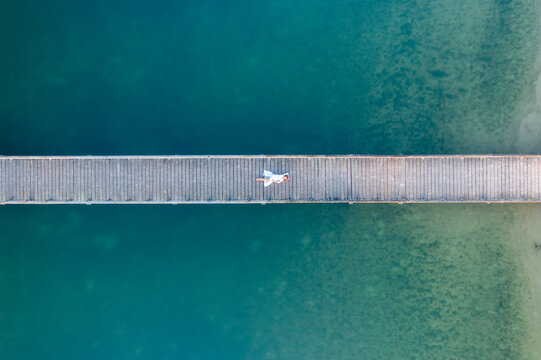 Aerial view of a woman laying down on the bridge at Henschotermeer lake in Woudenberg, Netherlands.