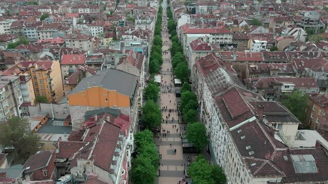 Tilt up of drone shot over Vitosha street, main walking street in Sofia, Bulgaria. Revealing National palace of culture and Vitosha mountain.