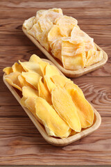 Dried pieces of mango and jackfruit lying on a bamboo plates on a wooden table. Macro. Closeup