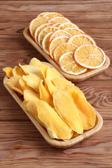 Dried pieces of mango and orange on a bamboo plates on a wooden table. Macro. Closeup