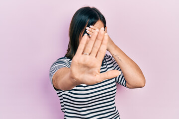 Young hispanic woman wearing casual clothes covering eyes with hands and doing stop gesture with sad and fear expression. embarrassed and negative concept.