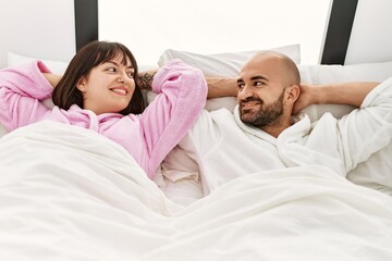 Young hispanic couple smiling happy relaxed with hands on head at bedroom.