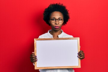 Young african american woman holding empty white chalkboard skeptic and nervous, frowning upset because of problem. negative person.