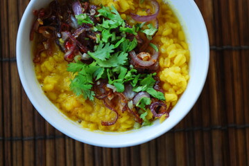 Gelbes Mung Daal mit roten Zwiebeln und Koriander auf Bambusmatte
