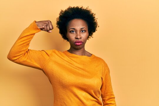 Young african american woman wearing casual clothes strong person showing arm muscle, confident and proud of power