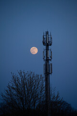 5G cell tower at night with full moon in the background
