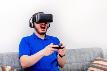 Man playing game using virtual reality headset and game joystick in the living room, at home.