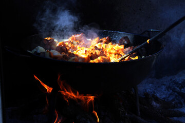 Closeup of a pan with migas and chorizo on the fire under the sunlight