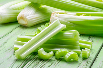 Pile of celery ribs on green wooden table. Healthy food background. - obrazy, fototapety, plakaty