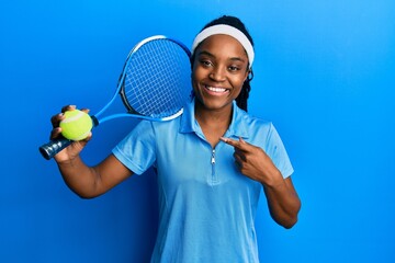 African american woman with braided hair playing tennis holding racket and ball smiling happy pointing with hand and finger