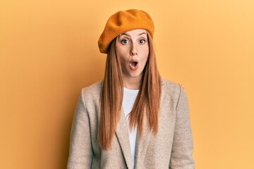 Young irish woman wearing french look with beret scared and amazed with open mouth for surprise, disbelief face