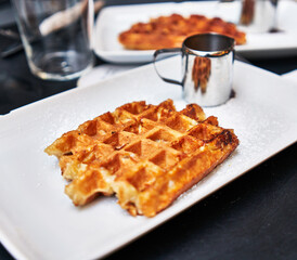  Two waffles and chocolate sauce on wooden surface