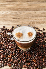  One cup of coffee with milk and coffee beans on wooden surface