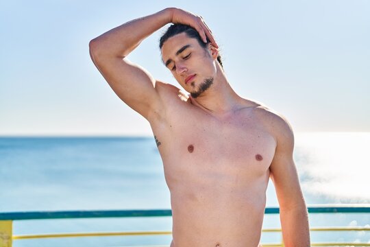 Young man stretching neck at seaside