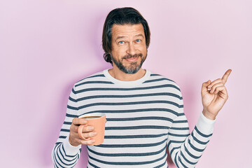 Fototapeta premium Middle age caucasian man drinking a cup of coffee smiling happy pointing with hand and finger to the side