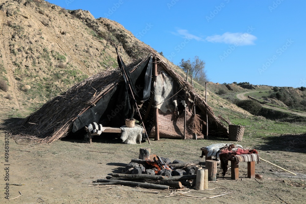 Wall mural A reed tent on a mountain slope. There are old furniture and fire in front of the tent. - Wall murals