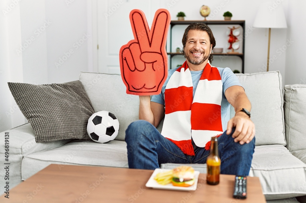 Sticker handsome middle age man football hooligan cheering game at home looking positive and happy standing 