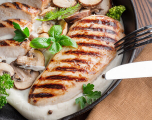 Roasted chicken fillet and mushrooms with herb in the frying pan on the wooden table close-up.