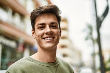 Young hispanic man smiling happy standing at the city.