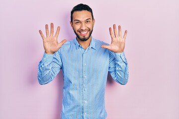 Hispanic man with beard wearing casual blue shirt showing and pointing up with fingers number ten while smiling confident and happy.