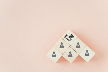 handshake icon screen on wooden cube block over employees on sweet pastel background with copy space for teamwork, brainstorming, cooperation for business growing concept