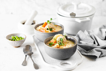 Soup with meatballs, cauliflower, baby peas, carrots and cream on a white background.