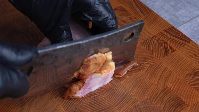 Closeup of chef cuts bacon guanciale into little cubes with old retro knife on wooden cutting board
