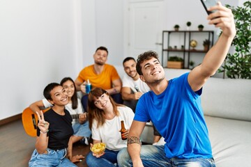 Group of young friends on party smiling happy make selfie by the smartphone at home.