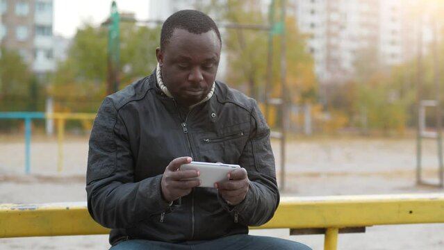 African american man plays the game on his smartphone