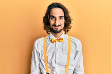 Young hispanic man wearing hipster elegant look puffing cheeks with funny face. mouth inflated with...