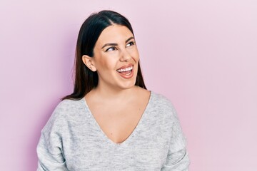 Fototapeta premium Young hispanic woman wearing casual clothes looking away to side with smile on face, natural expression. laughing confident.