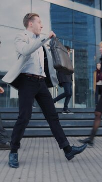 Cheerful Young Businessman is Actively Dancing on a City Street. Office Manager Moves Through Busy Office Crowds Commuting to Work. Video Footage with Vertical Screen Orientation 9:16.Smartphones.