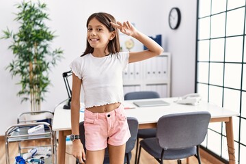 Young hispanic girl standing at pediatrician clinic smiling pointing to head with one finger, great idea or thought, good memory