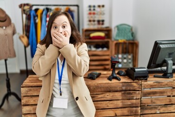 Young down syndrome woman working as manager at retail boutique shocked covering mouth with hands for mistake. secret concept.