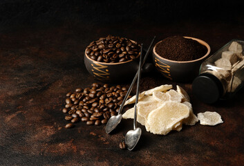 Bowls with dried ginger, brown lump and granulated sugar, coffee beans and ground coffee as ingredients on a dark background.
